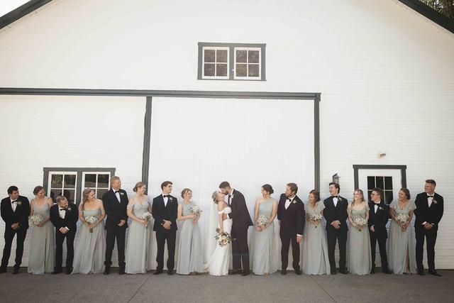 Wedding party lined up in front of the white barn doors