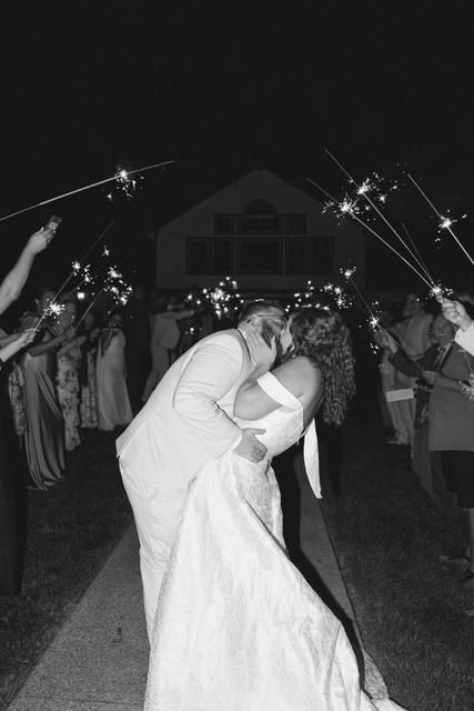 Couple kissing during a sparkler send-off in front of the barn at night