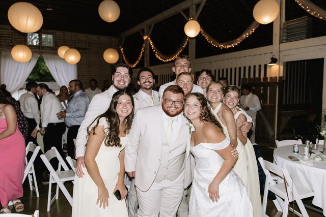 Wedding party smiling together in the barn reception under paper lanterns