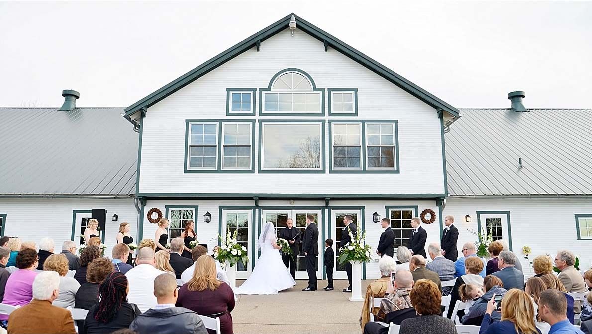 Guests watch a ceremony at the front of the white barn