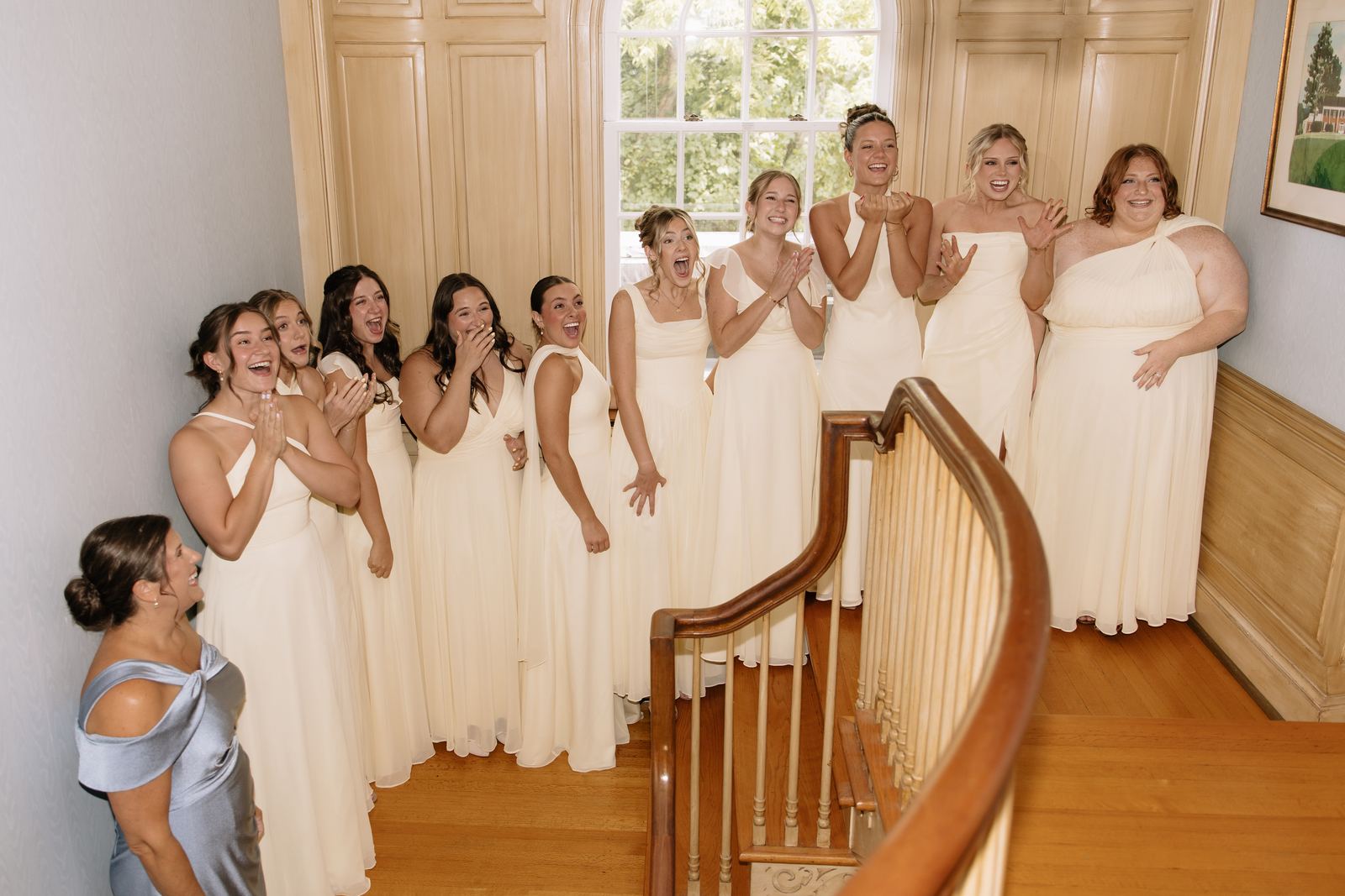 Bridesmaids cheering at the top of the curved house staircase