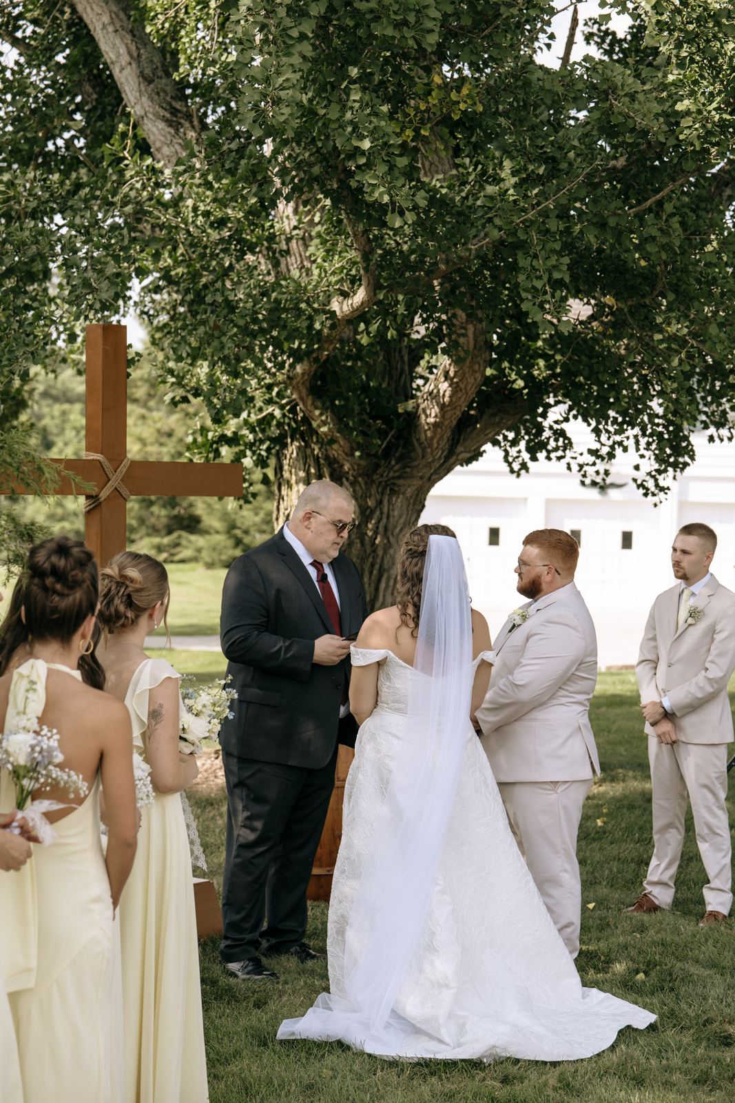 Couple exchanging vows beneath the ginkgo tree beside the wooden cross