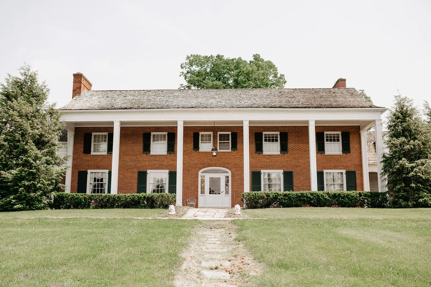 Front of the brick estate house with white columns