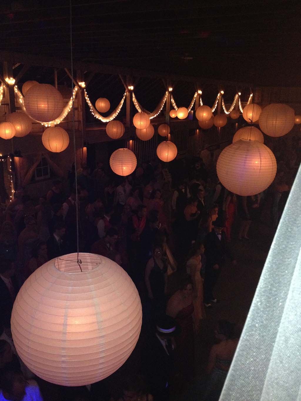 Couple dancing at night between white curtains with glowing lanterns behind them