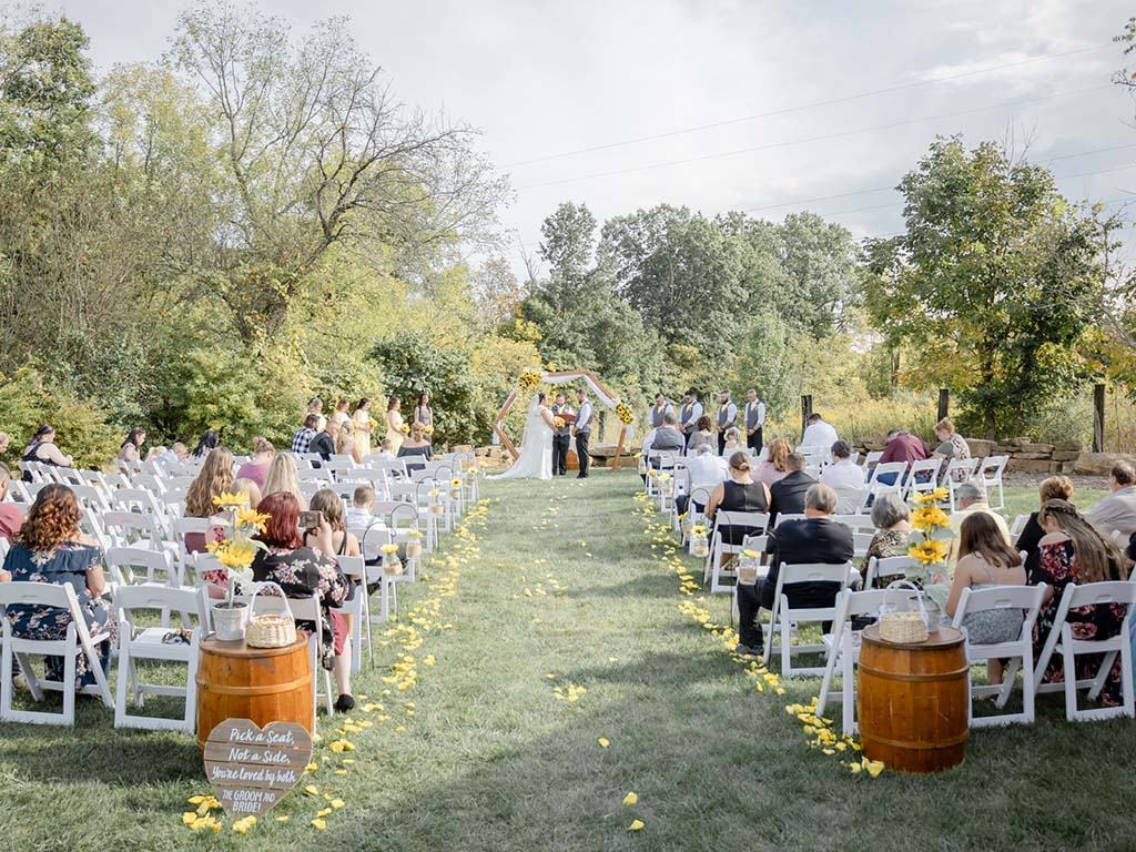 Meadow ceremony with a sunflower-lined aisle